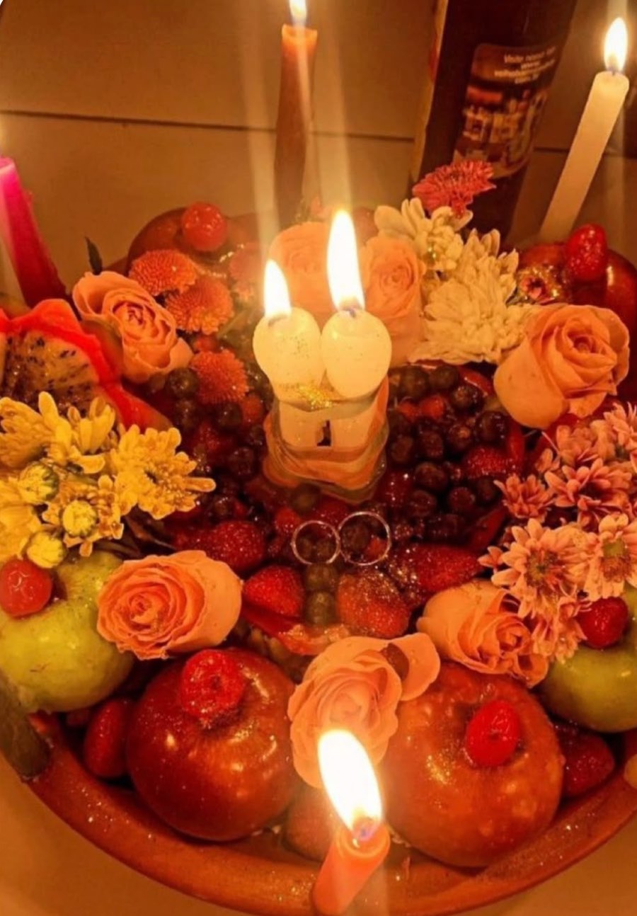 Trabalho de união amorosa montado por Yasmin: alianças, velas de casal, frutas e flores em oferenda